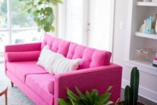 a neutral living room with a hot pink sofa for a color statement, potted plants in baskets and built-in storage units