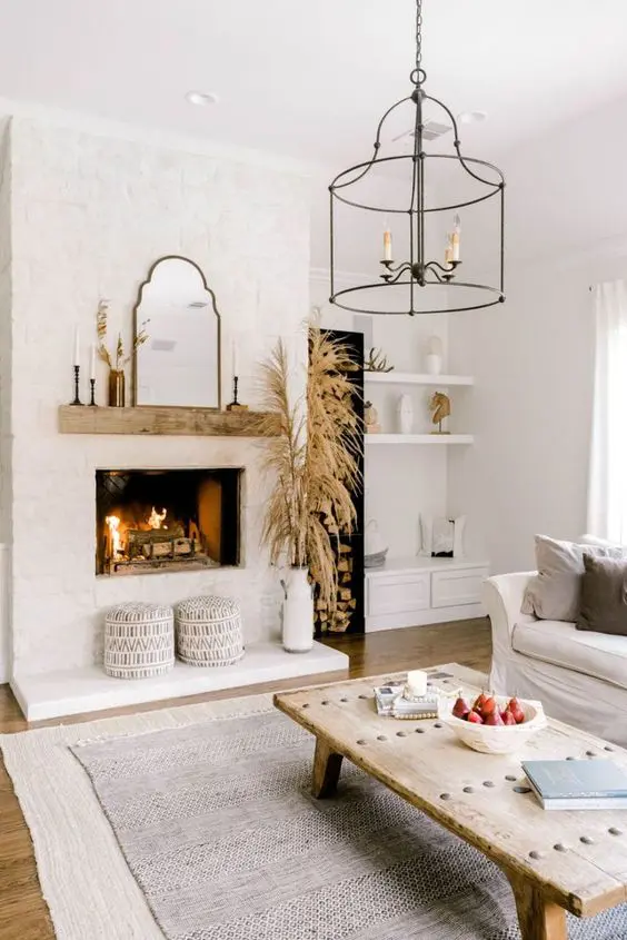 a neutral modern country living room with a fireplace clad with brick, a low coffee table, neutral furniture and layered rugs