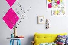 a pretty and bright interior with a lemon yellow loveseat, a table with blue legs, a colorful gallery wall and hot pink geometric decor