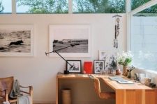 a refined modern country home office with a corner wooden desk, leather chairs, a small gallery wall and some blooms