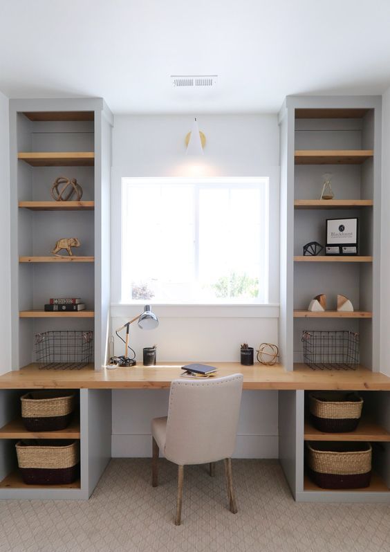 a small modern country home office in dove grey, with built-in shelvin units and a desk, an upholstered chair and a sconce