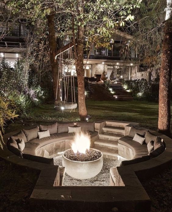 a small sunken patio with a fire pit and built-in round benches with pillows is a lovely space to relax in the evening