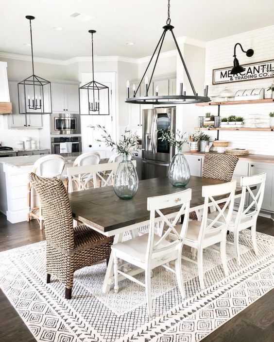 a stylish modern country dining space with a stained table, woven and wooden chairs, a metal chandelier and a buffet at the wall