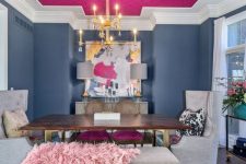 a unique dining room with navy walls and a hot pink ceiling, a wooden table and upholstered chairs, a gold chandelier