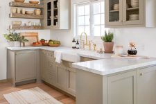 a welcoming dove grey modern country kitchen with shaker style cabinets, white marble countertops, a white tile backsplash and open shelves