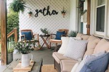 a welcoming farmhouse porch with a large wicker sofa, a chest coffee table, rattan rockers, potted greenery and a vintage chandelier