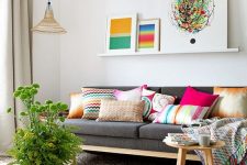 a welcoming living room with a grey sofa, a ledge gallery wall with bright artworks, hot pink accessories and a bold mosaic tile floor
