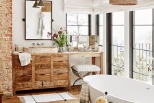 a welcoming modern country bathroom with exposed brick, a stained floor, a stained vanity, a woven lampshade and chic appliances