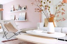 an airy and dreamy living room with a light pink accent wall, chic Scandinavian furniture, low coffee tables, a cool artwork and ledge gallery walls