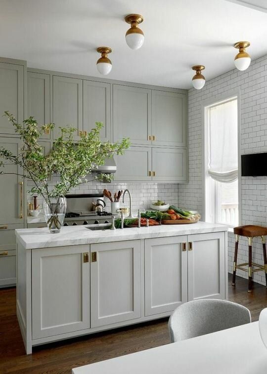 an amazing pale green modern country kitchen with shaker cabients, white subway tiles, brass touches for extra elegance