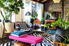 an eclectic attic space with an extended brick wall, wooden beams on the ceiling, a sofa, a hot pink bench and potted plants is cool