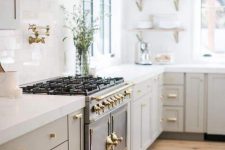 an elegant light grey modern country kitchen with white stone countertops, a vintage cooker and a chic hood plus open shelves