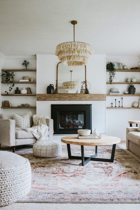 An elegant modern farmhouse living room with a built in fireplace, built in wooden shelves, chic neutral furniture, a tassel chandelier