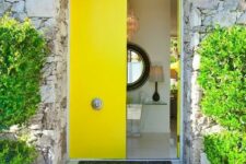 sleek bold yellow double-height doors with refined antique knobs is a gorgeous statement with both color and style of the doors