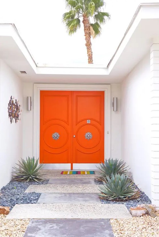 Super bright orange front doors with refined vintage knobs are a great example of chic mid century modern decor style to go for