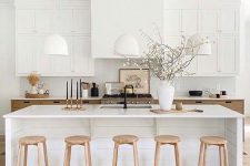 02 a beautiful millennial kitchen in two tones, light stained and white, a large kitchen island, wooden stools and white pendant lamps