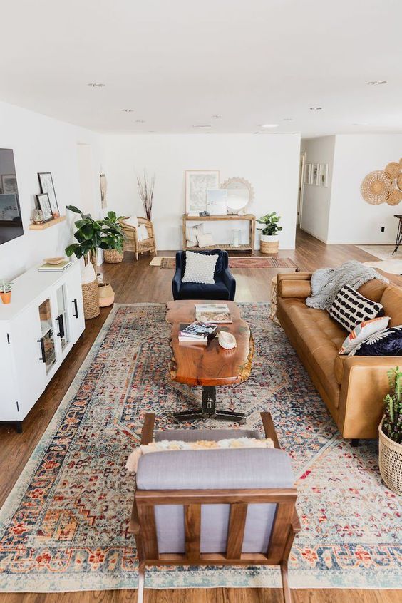 a stylish mid-century modern farmhouse living room with a leather sofa, elegant chairs, a living edge table, potted plants