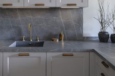 08 a modern grey kitchen with a grey marble backsplash and countertops, brass fixtures is a very chic and bold solution