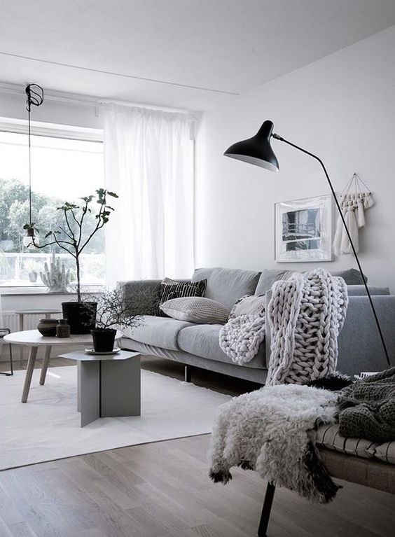 a dreamy Scandinavian living room in white, black and grey, with a comfy sofa, grey chairs, black accessories for more drama