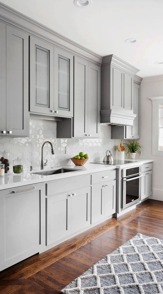 a beautiful dove grey modern farmhouse kitchen with a white Moroccan tile backsplash and white stone countertops plus neutral fixtures