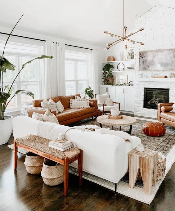 A welcoming mid century modern living room with a built in fireplace, a white and rust colored sofa, a woven bench, potted plants