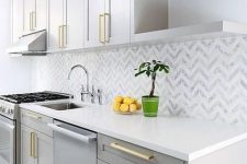 11 a glam grey kitchen with white stone countertops, a chevron tile backsplash and gold fixtures is a cool and shiny space