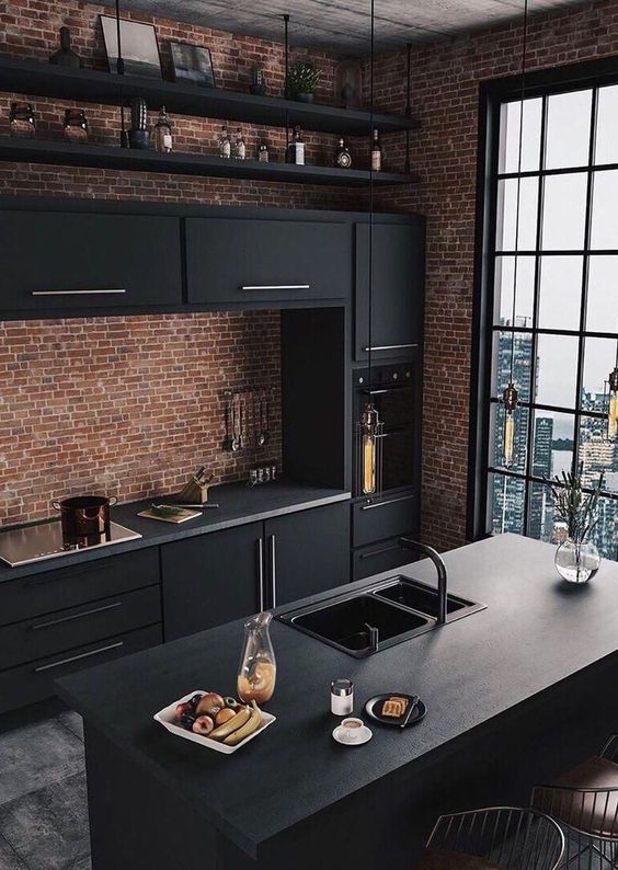 a fantastic industrial kitchen with red brick walls, black metal cabinets, concrete countertops and bulbs hanging over the space