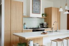 17 a serene Scandinavian kitchen with light stained cabinets, a large kitchen island with open shelves, a blue tile backsplash and plywood stools