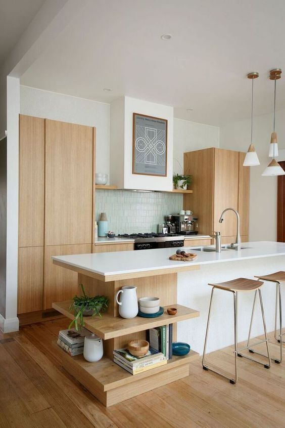 a serene Scandinavian kitchen with light stained cabinets, a large kitchen island with open shelves, a blue tile backsplash and plywood stools