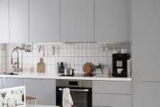 21 a modern grey kitchen with sleek cabinets, a white tile backsplash, a small table and woven chairs plus a striped rug
