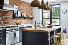 22 a chic kitchen with navy cabinets, a red brick wall, a navy kitchen island with a butcherblock countertop, metal pendant lamps