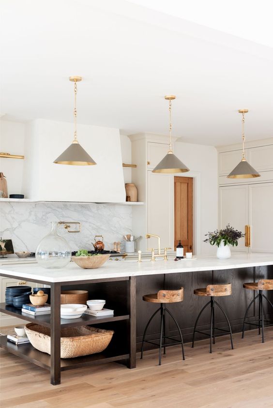 a chic farmhouse kitchen with white shaker style cabinets, a dark stained kitchen island with open shelves, grey pendant lamps