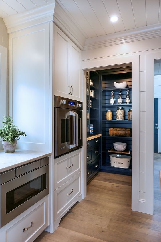 a small pantry integrated right into the kitchen and matching it in style but done in a contrasting navy color