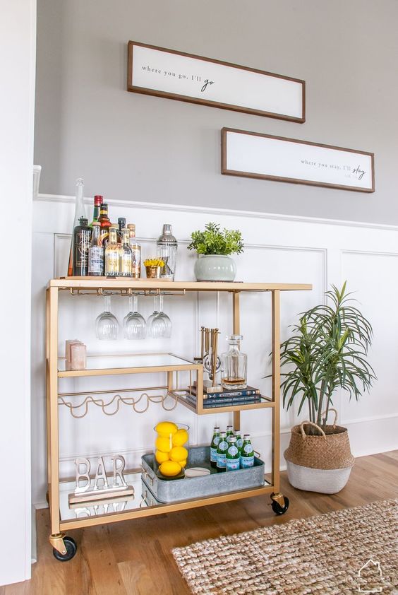 a stylish gold cart with various mirror shelves, stylish with a sign and some lemons ina  glass is a very chic idea