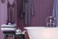 a gorgeous purple bathroom with a planked wall
