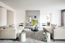 a beautiful contemporary living room with floating shelves and a mirror, creamy sofas, stone side tables, a catchy coffee table and lots of accessories