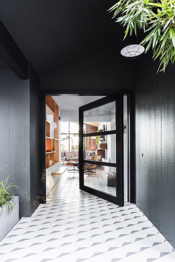 a black frame and glass pivot entrance door looks amazing with geometric tiles on the floor and makes a statement