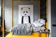 a bold contemporary bedroom with a yellow canopy bed on a yellow lit up platform, grey bedding, a round chandelier and a statement wall art