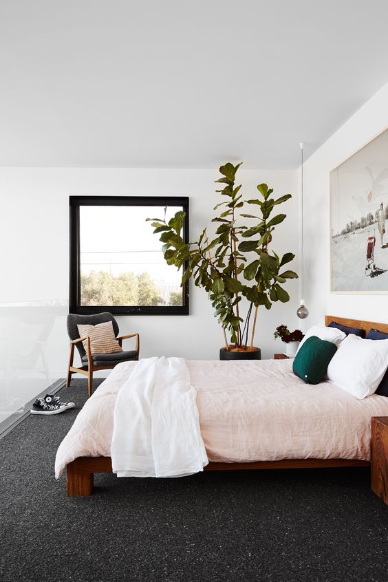 a chic bedroom with stained furniture, pastel bedding, a statement artwork and a statement potted plant is very welcoming