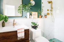 a chic modern bathroom with a green accent wall and a green mosaic tile floor, a stained vanity, an arched mirror and potted plants