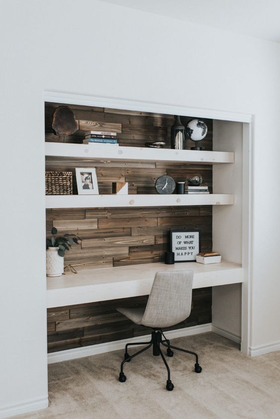 A contemporary built in home office nook with wood tiles, open shelves and a matching desk, decor and a grey chair