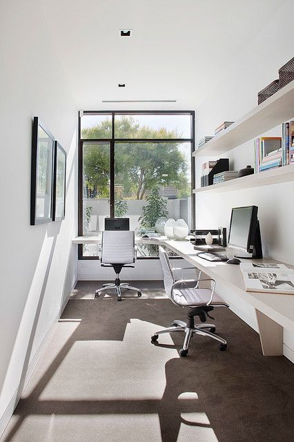 a contemporary home office with a floor to ceiling window, a large corner desk, leather chairs, open shelves and a mini gallery wall