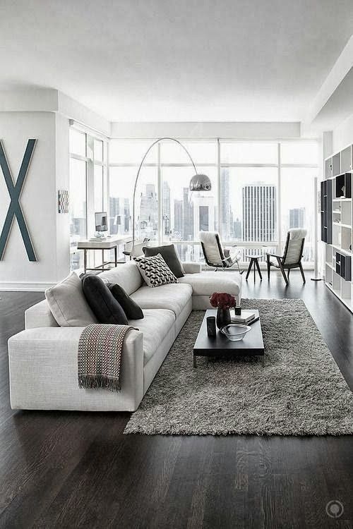 a contemporary living room with a creamy sectional sofa, a grey rug and textiles, printed pillows, a cool floor lamp and a sitting zone by the window