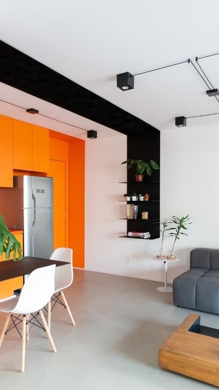 A contemporary open layout with a black and white accent and a whole orange accent wall with orange cabinets and a door is very bold