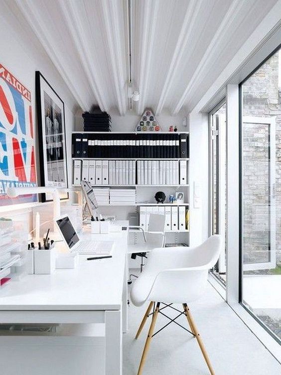 a contemporary shared home office in black and white, with a glazed wall, a double white desk and chairs, cool artworks and open shelves for storage
