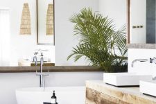 a contemporary tropical bathrom with a mirror that takes a whole wall, a wooden vanity, a tub, a basket and some potted plants