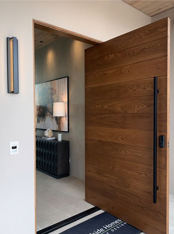 a cool and heavy wood pivot door with a black long handle is a beautiful and lovely idea for a modern entrance