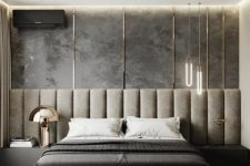a cool contemporary bedroom with a grey accent wall and a grey upholstered bed with an extended headboard, built-in nightstands and edgy pendant lamps