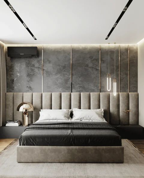 A cool contemporary bedroom with a grey accent wall and a grey upholstered bed with an extended headboard, built in nightstands and edgy pendant lamps