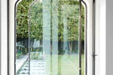 a delicate and catchy arched glass pivot door that leads to the garden is a lovely idea for an elegant home
